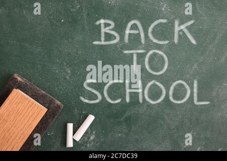 Tableau noir de classe sale avec message de rentrée et craie blanche et gomme de près. Vue de dessus Banque D'Images