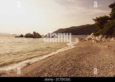 La côte et la plage de l'île grecque de Skopelos des Sporades en plein soleil et à l'aspect orange. Banque D'Images