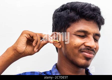 Retirez la cire d'oreille en toute sécurité - un homme nettoie l'oreille avec des cotons-tiges gros plan. Oreille de nettoyage avec un coton-tige oreille sale. Retirer la cire d'oreille à l'aide d'un coton-tige Banque D'Images