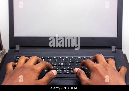 Travail à domicile - les mains de l'homme utilisant un ordinateur portable avec écran sur le bureau à l'intérieur de la maison. Image de style maquette d'une main utilisant et touchant un ordinateur portable sur la table du hom Banque D'Images