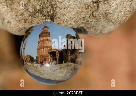 Gros plan de la réflexion du temple de Qutub Minar dans une boule de verre près d'une roche Banque D'Images