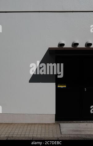 MATSUYAMA, JAPON - 23 septembre 2019 : une prise de vue verticale de caméras de sécurité à dôme blanc sur un mur avec porte marron Banque D'Images