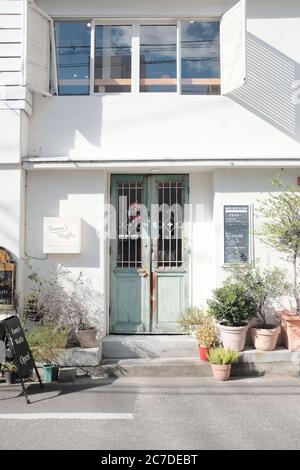 MATSUYAMA, JAPON - 23 septembre 2019 : un cliché vertical de pots de fleurs devant une maison blanche avec des portes bleues Banque D'Images