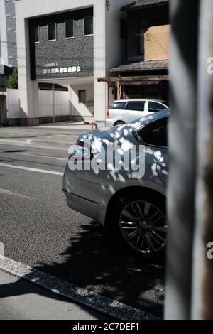 MATSUYAMA, JAPON - 23 septembre 2019 : un cliché vertical sélectif du feu arrière d'une voiture blanche garée dans la rue à proximité des bâtiments Banque D'Images