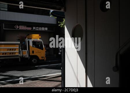 MATSUYAMA, JAPON - 23 septembre 2019 : un camion jaune stationné près d'une porte de garage fermée à volet roulant en acier Banque D'Images