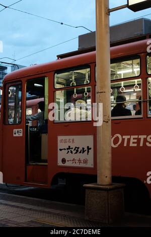 MATSUYAMA, JAPON - 21 septembre 2019 : un cliché vertical d'un bus rouge avec portes automatiques ouvertes à un arrêt de bus Banque D'Images