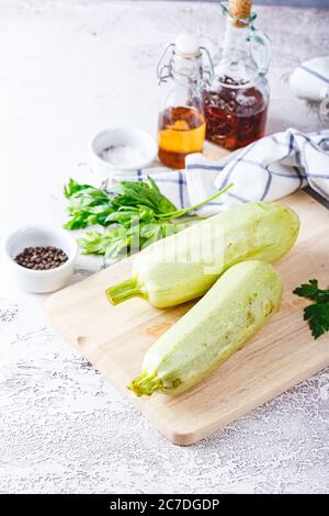 Deux courgettes fraîches sur une planche à découper en bois sur fond blanc Banque D'Images