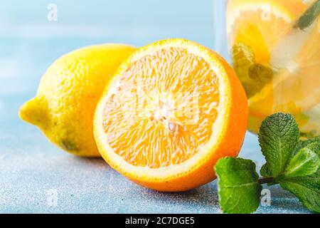 Citron, feuilles de menthe et orange pour des cocktails rafraîchissants, limonade ou mojito sur fond bleu clair. Banque D'Images