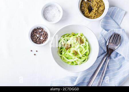 Des nuddles de Zucchini sains avec du pesto sur fond blanc. Vue de dessus. Banque D'Images