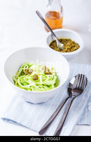 Des nuddles de Zucchini sains avec du pesto sur fond blanc Banque D'Images