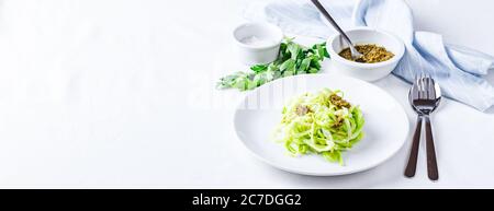 Des nuddles de Zucchini sains avec du pesto sur fond blanc. Placer pour le texte. Longue bannière large Banque D'Images