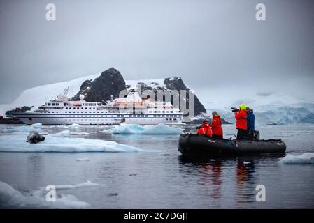 Portrait d'un phoque léopard, Hydrurga leptonyx, reposant sur un floe de glace. Touristes explorant avec zodiac Paradise Bay Antarctique péninsule Antarctique. Le Banque D'Images