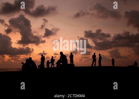 Silhouette d'un groupe de personnes sur la plage ayant discussions de groupe sous le beau ciel nuageux Banque D'Images