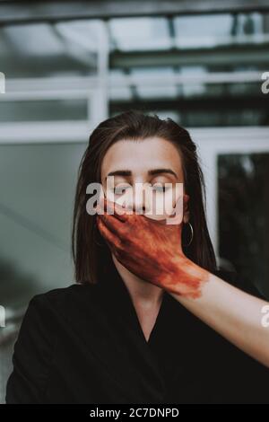 main peinte en rouge couvrant la bouche d'une femelle avec des yeux fermés. Concept de silence Banque D'Images