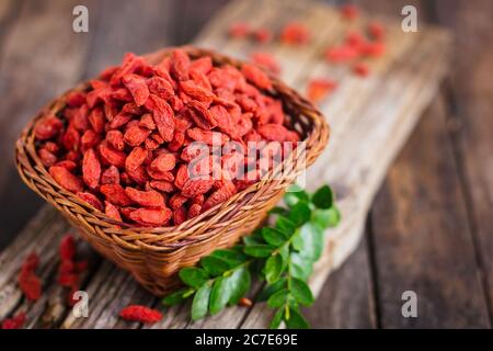 Baies de Goji dans le panier sur la table rustique Banque D'Images