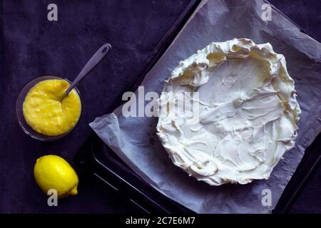Base de meringue maison pour gâteau Pavlova avec caillé de citron. Dessert croustillant sur fond noir Banque D'Images