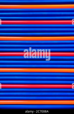 Les tubes en plastique à motif bleu, rouge et orange ont un arrière-plan de pailles Banque D'Images
