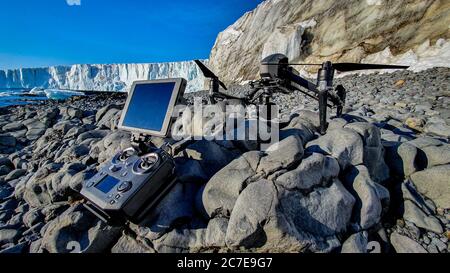 Drone et contrôleur assis sur des rochers avec glacier en arrière-plan Banque D'Images