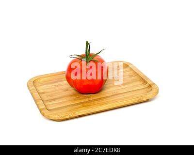 Tomates, tomates de brousse avec tige, grandes, sur un panneau en bois devant un fond blanc. Banque D'Images