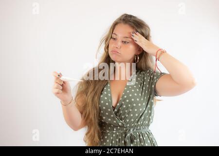 Jolie fille blonde dans une robe verte regardant le test avec le geste de préoccupation Banque D'Images