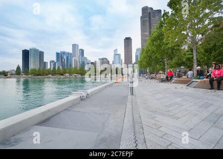 Chicago USA - août 27 2015 ; promenade au bord de l'eau, sur le lac Michigan, avec des personnes assises sous des arbres entourés de grands gratte-ciel de la ville. Illinois, États-Unis Banque D'Images