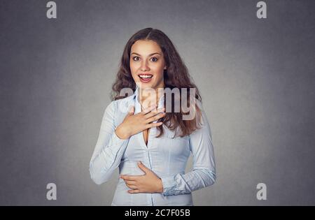 Jeune femme stupéfaite regardant la caméra isolée sur fond gris studio. Mannequin fille avec de longs cheveux ondulés bouclés en chemise bleue formelle. Gros plan portrait. Banque D'Images