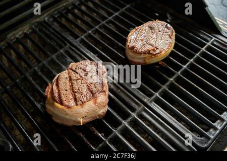 Steaks de filet épais enveloppés de bacon sur un barbecue à gaz. Banque D'Images