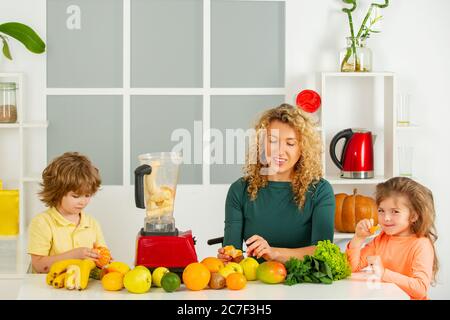 Portrait de famille mignonne est de faire jus de fruit. Sur la cuisine blanche. Banque D'Images