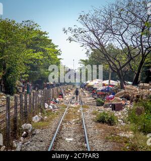 Une personne marchant le long des voies ferrées du chemin de fer circulaire Yangon au Myanmar Banque D'Images