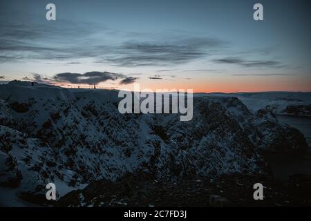 Photo en grand angle du coucher du soleil sur un paysage montagneux enneigé à Nordkapp, Norvège Banque D'Images