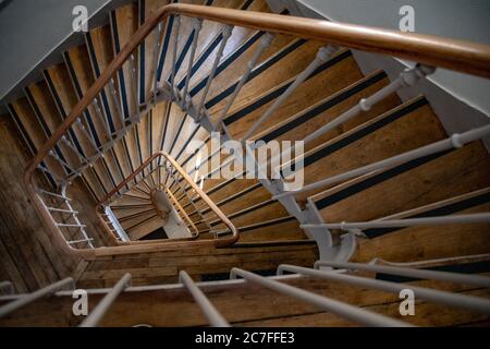 Vue de dessus sur les escaliers en spirale d'époque du bâtiment ancien. Détails architecturaux de style français de l'escalier avec marches en bois et rambardes en métal ornées Banque D'Images