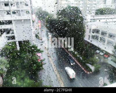 pluie sur la rue, vue aérienne. chute d'eau sur la fenêtre de l'appartement en verre. vue sur la route pendant la tempête. rue humide et conduite prudente Banque D'Images