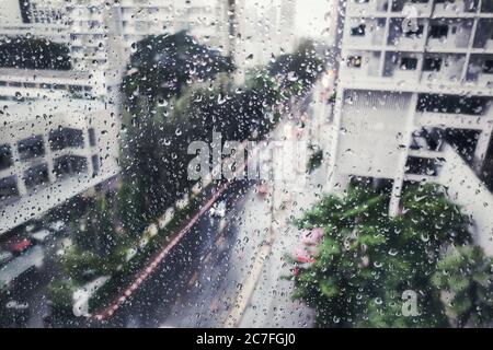 pluie sur la rue, vue aérienne. chute d'eau sur la fenêtre de l'appartement en verre. vue sur la route pendant la tempête. rue humide et conduite prudente Banque D'Images