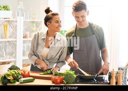 Une alimentation saine à la maison. Le couple heureux aimant prépare le bon repas dans la cuisine. Banque D'Images