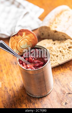 Haricots rouges en conserve dans la sauce tomate dans la boîte de conserve sur la table de cuisine. Banque D'Images