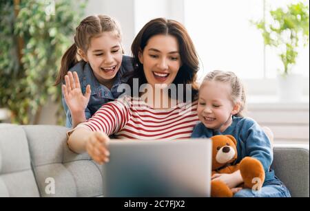 Famille heureuse et aimante. Jeunes filles et mères utilisant un ordinateur portable. Maman drôle et les enfants adorables s'amusent à rester à la maison. Banque D'Images