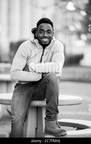 Prise de vue verticale en niveaux de gris d'un homme afro-américain souriant à l'appareil photo Banque D'Images