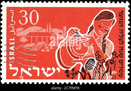 ISRAËL - VERS 1955 UN timbre imprimé en Israël, montre une jeune femme arrossant des fleurs , émis en l'honneur du 20e anniversaire de jeunes immigrants - Aliyah , Banque D'Images