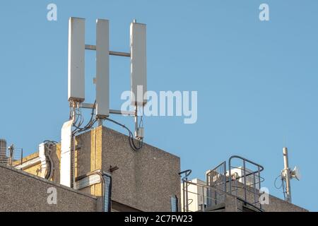 Vue isolée des antennes réseau de téléphone récemment installées, vue au sommet du bloc de bureau. Les détails des mâts, du câblage et du cheminement des câbles sont visibles. Banque D'Images