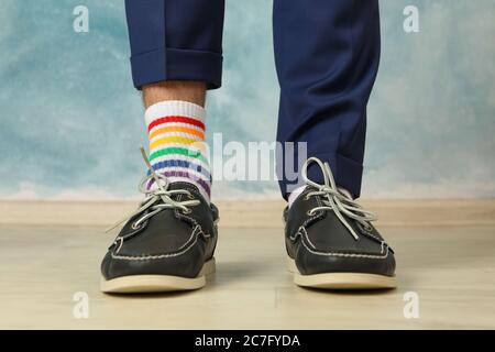 Homme dans un pantalon bleu, des mocassins et des chaussettes LGBT sur fond bleu Banque D'Images