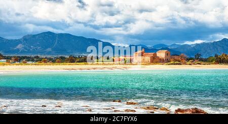 La baie et la plage de Nora, l'église médiévale Sant'Efisio près de la rive et des montagnes en arrière-plan. Situation: Nora, Pula, Sardaigne, Italie Europe Banque D'Images