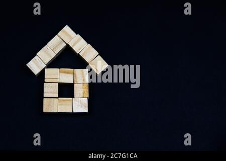 Une maison de blocs de bois sur fond sombre. Le concept de l'immobilier, de la construction de maisons, de l'assurance, du logement, de la famille. Le toit et les murs de cu Banque D'Images