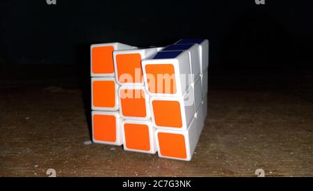 Gros plan d'un cube de Rubik résolu sur un bois surface avec arrière-plan noir Banque D'Images