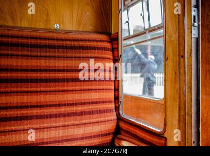 Vue rapprochée d'un siège de train de première classe vintage avec fixations d'éclairage vintage dans un compartiment de train. Banque D'Images