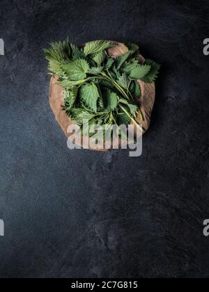 Bol en bois de feuilles d'ortie fraîchement récoltées. Banque D'Images