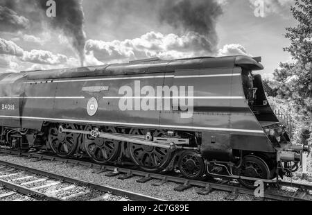 Vue latérale d'une majestueuse locomotive à vapeur britannique vue faisant place sur une voie ferrée près d'une grande ville britannique. Banque D'Images