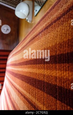 Vue rapprochée d'un siège de train de première classe vintage avec fixations d'éclairage vintage dans un compartiment de train. Banque D'Images