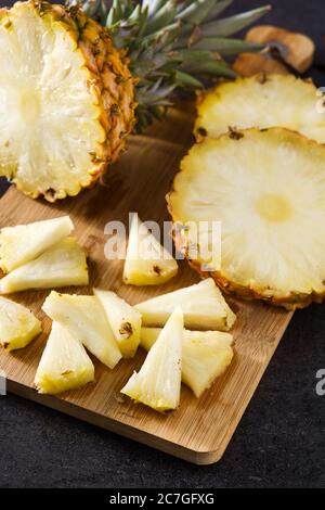 Tranches d'ananas frais sur le plan de coupe et fond en pierre noire Banque D'Images