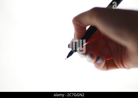 Stylo dans une main femelle sur fond blanc. Vue latérale, mise au point sélective. Banque D'Images