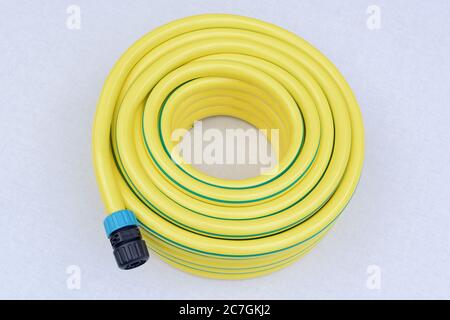 Tuyau flexible en plastique jaune enroulé avec connecteur sur fond blanc Banque D'Images
